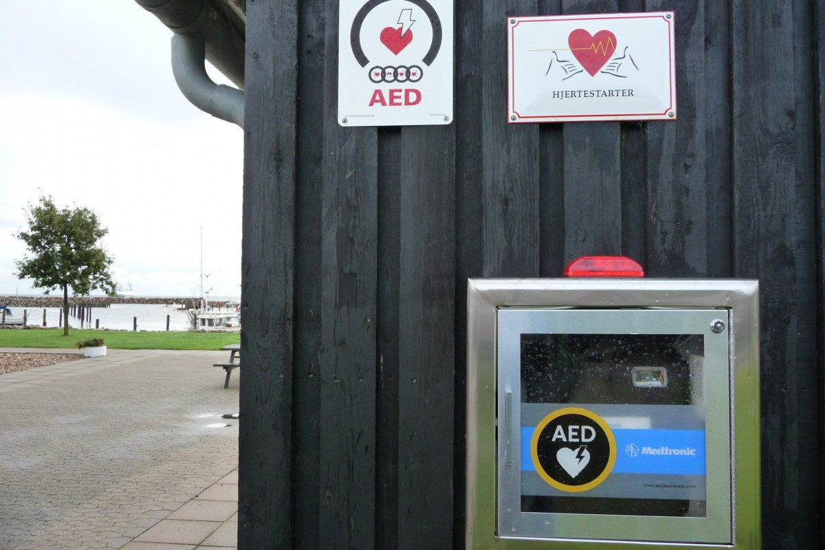 Mit gut sichtbaren Hinweisschildern versehener Defibrillator in einem dänischen Hafen.